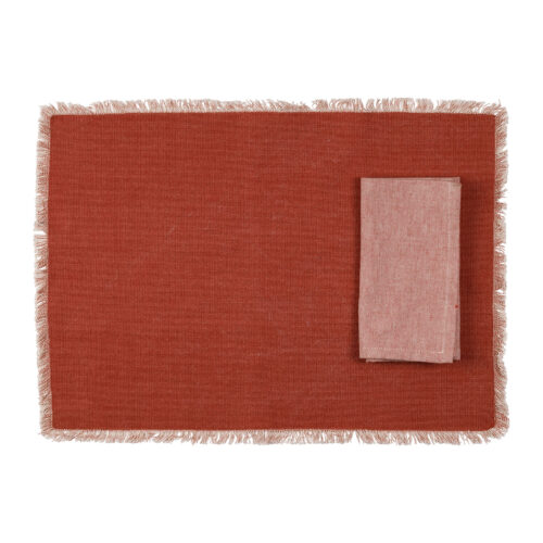 Individual retangular vermelho com franjas claras e guardanapo dobrado sobre o lado direito
