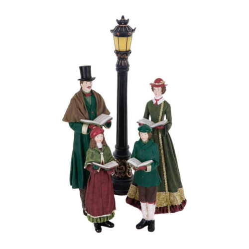 Figuras de um coro de Natal em tons verdes junto a um candeeiro.